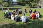 Gruppe von Schülern mit und ohne Handicap sitzen auf der Wiese des Parks im Kreis