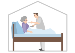 Eine ältere Dame liegt zuhause im Bett und wird von einem Pfleger versorgt.