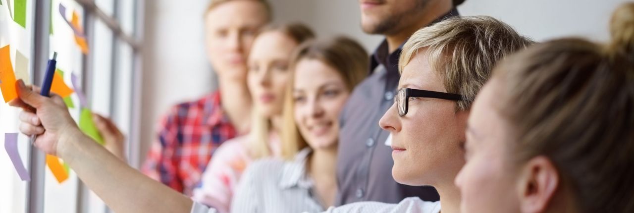 Frau befestigt mit Gruppe Notizzettel an Wand