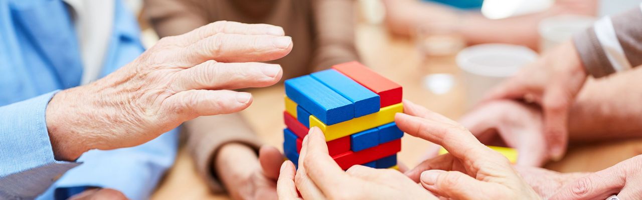 Hände, die Turm aus bunten Bausteinen bauen