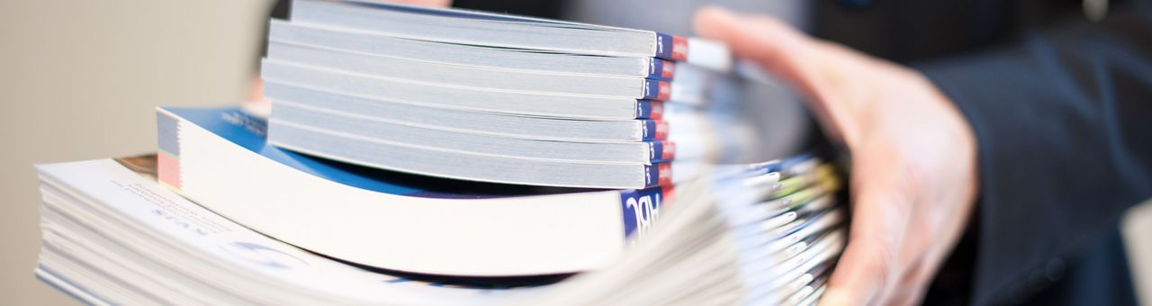 Frau trägt einen Stapel Zeitschriften