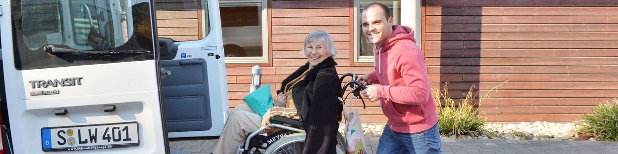 Ein Mann hilft einer Frau mit Rollstuhl