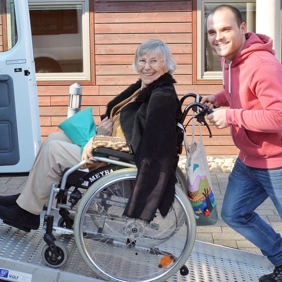 Ein Mann hilft einer Frau mit Rollstuhl