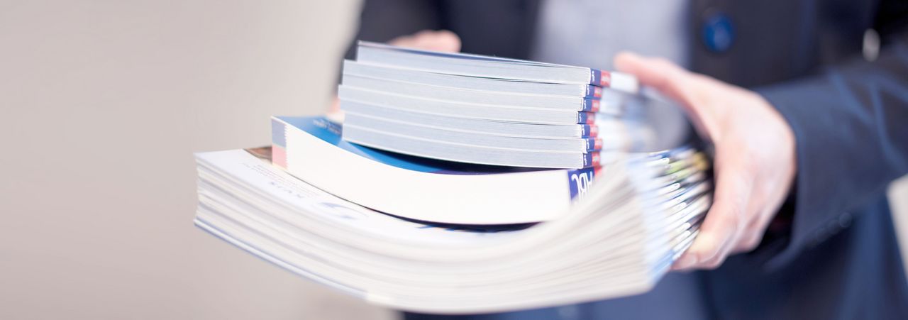 Frau trägt einen Stapel Zeitschriften