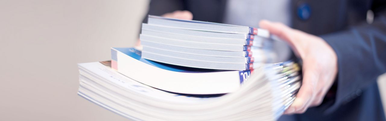 Frau trägt einen Stapel Zeitschriften