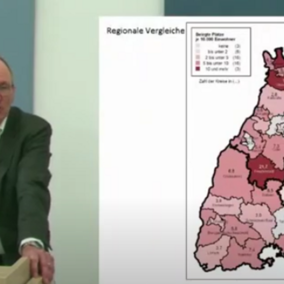 Ein Referent am Podium; Daneben ist eine Folie mit einer Baden-Württemberg-Karte eingeblendet